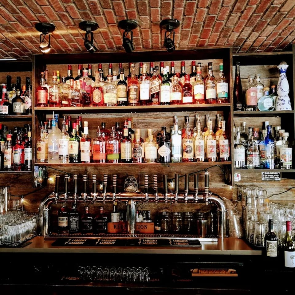 A well-stocked bar at Vauxhall, featuring numerous liquor bottles, beer taps, and glassware.
